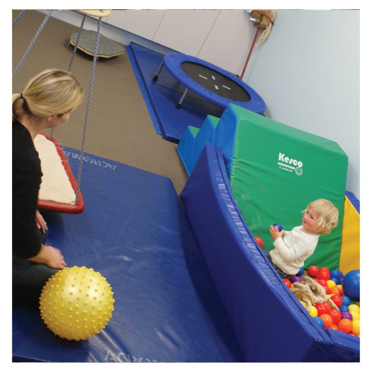 Child in ball pit looking at staff member