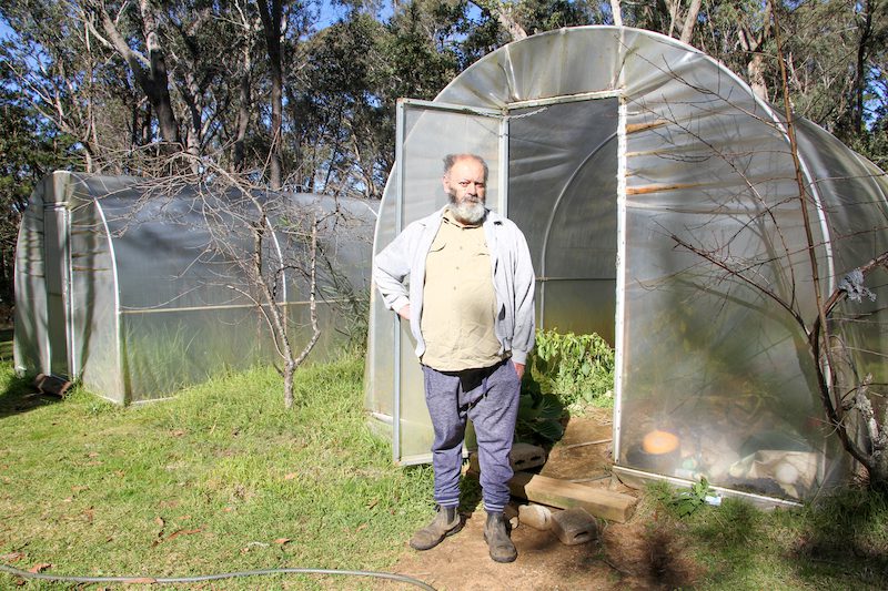 Frank standing near his greenhouses