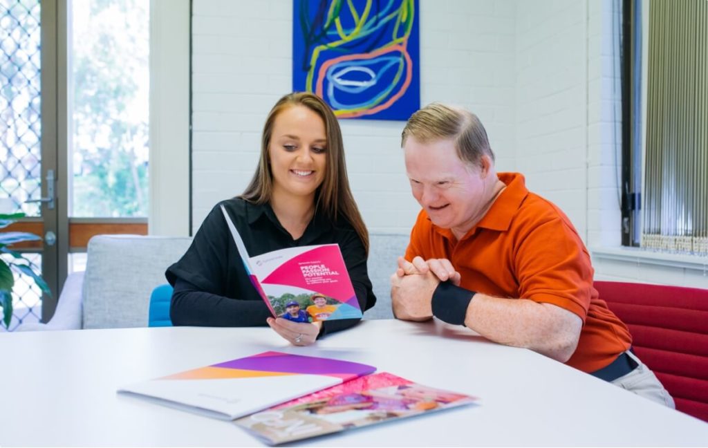 Support coordinator showing a brochure to a Sylvanvale resident