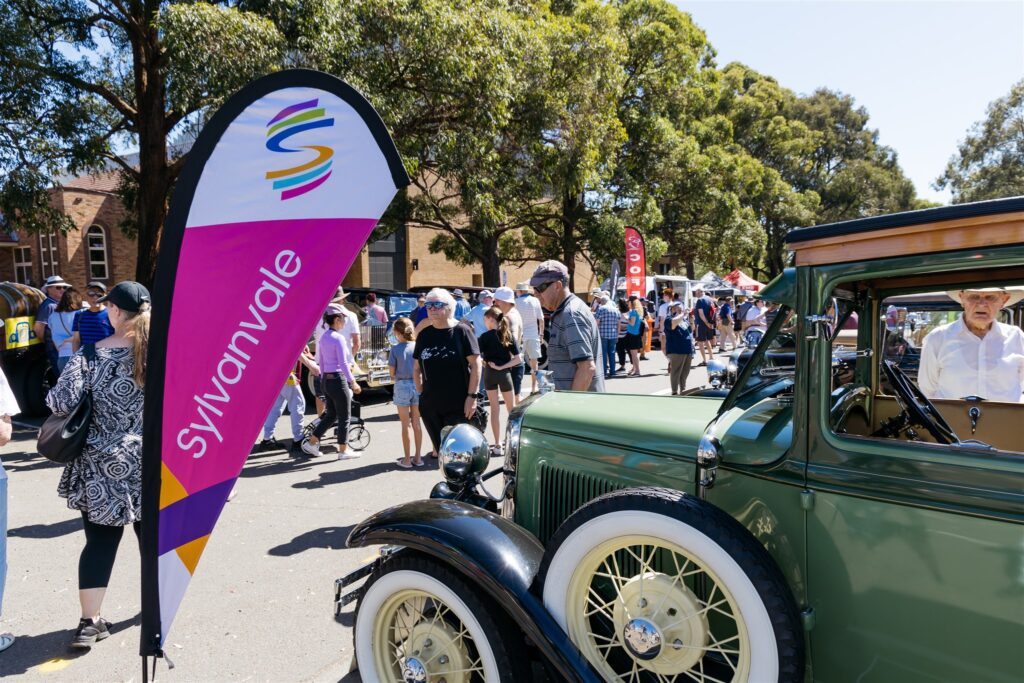 Vintage cars surrounded by people walking and viewing